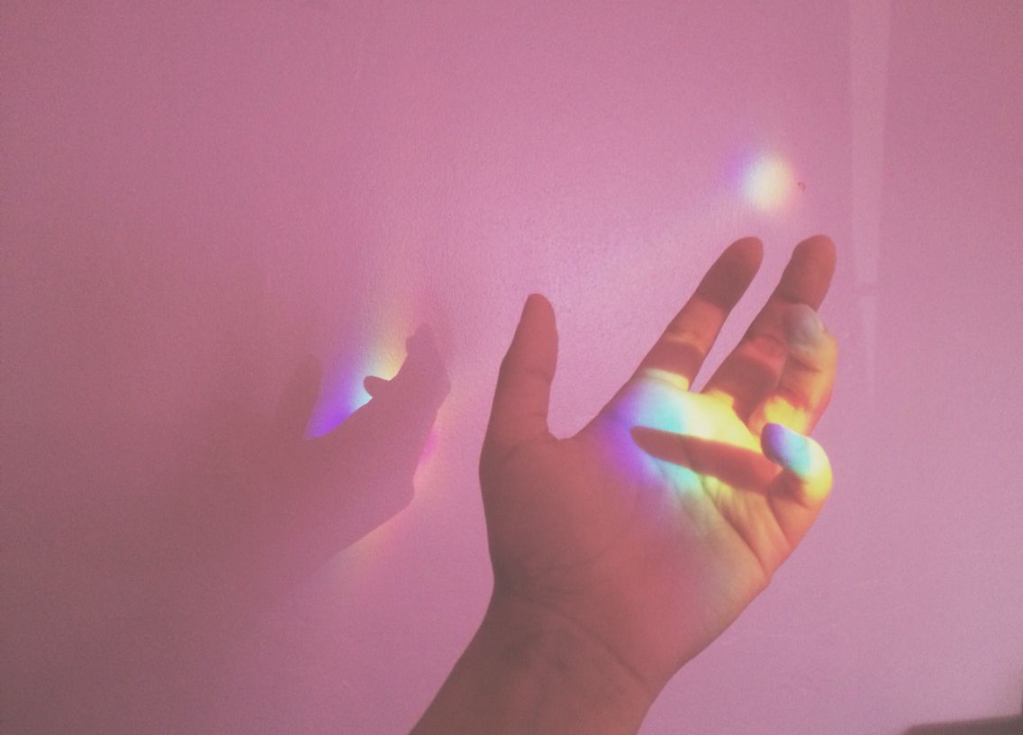 a hand slightly touching the wall with the color spectrum illuminating the palm of the hand